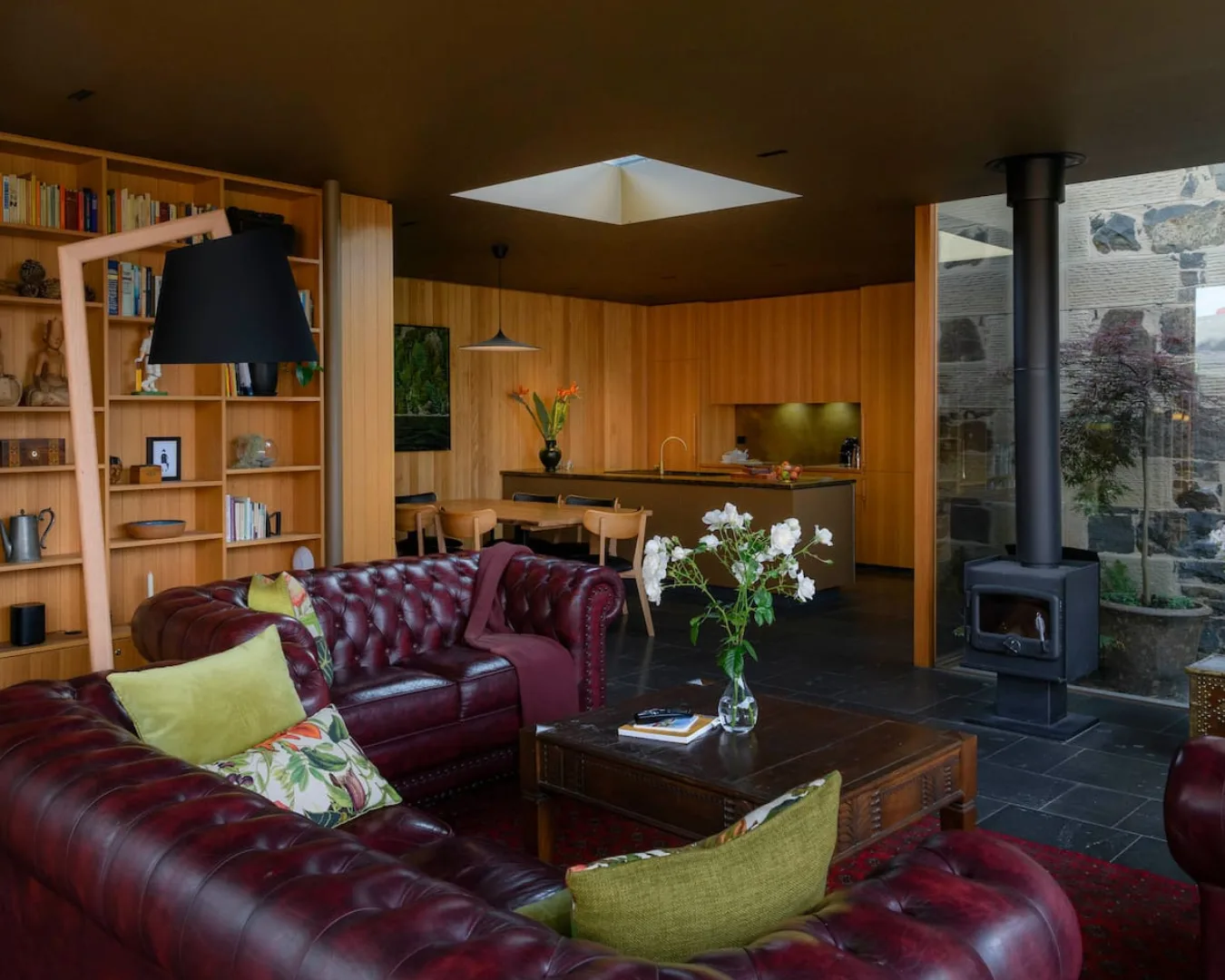 A wood-panelled living room with burgundy couches and a fireplace for cold Hobart winters.