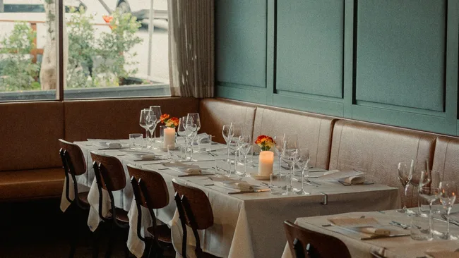 Restaurant Labart&rsquo;s dining room, with white-clothed tables set with lit candles, plates and glasses ready for diners.