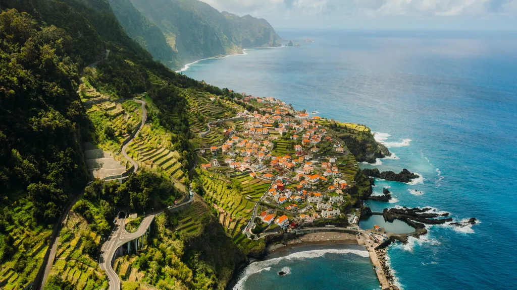 scenic road to the city of Seixal surrounded by Atlantic Ocean and dramatic green mountain peaks in Madeira, Portugal