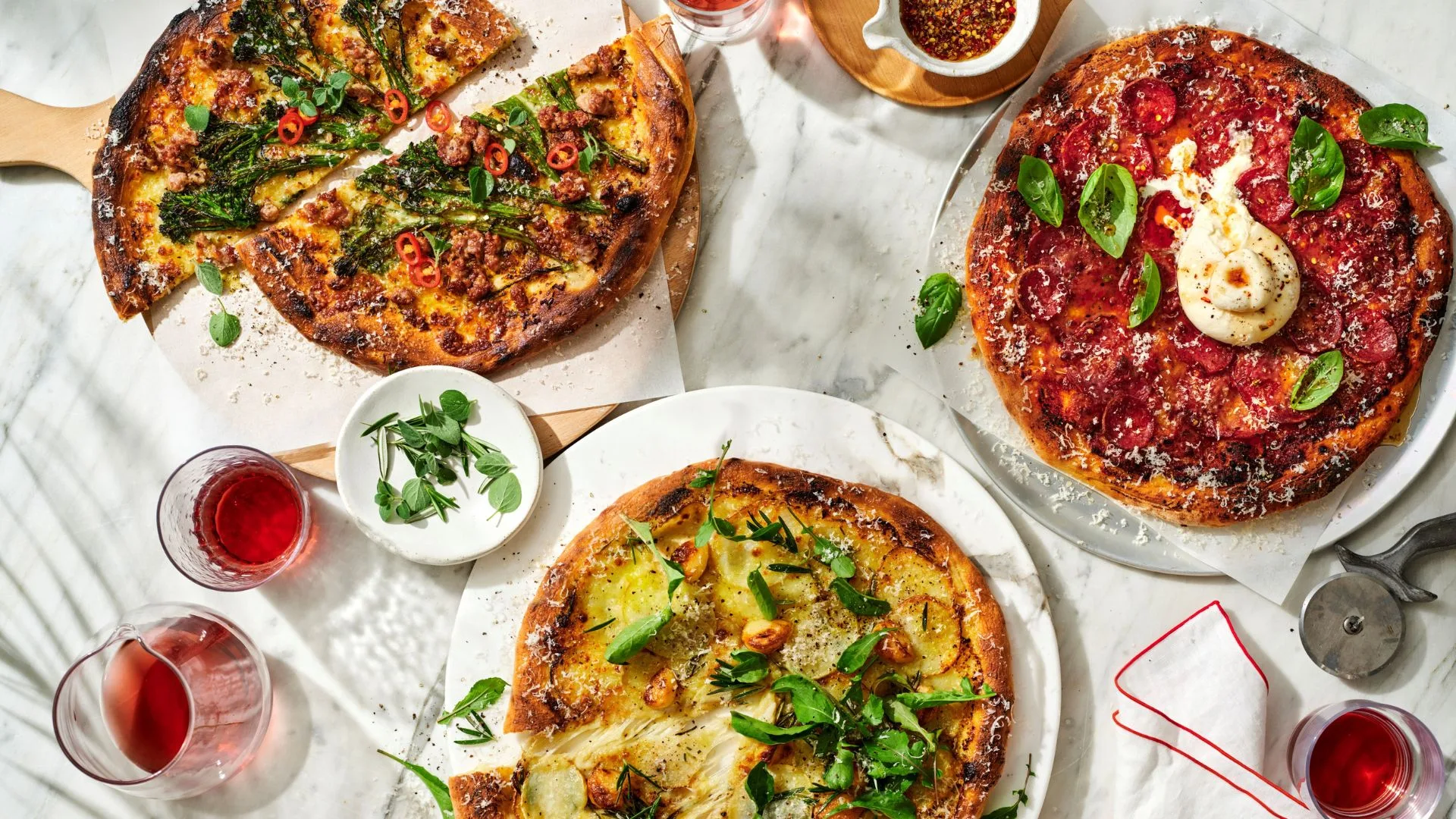 Three different pizzas on a table to represent different Italian recipes