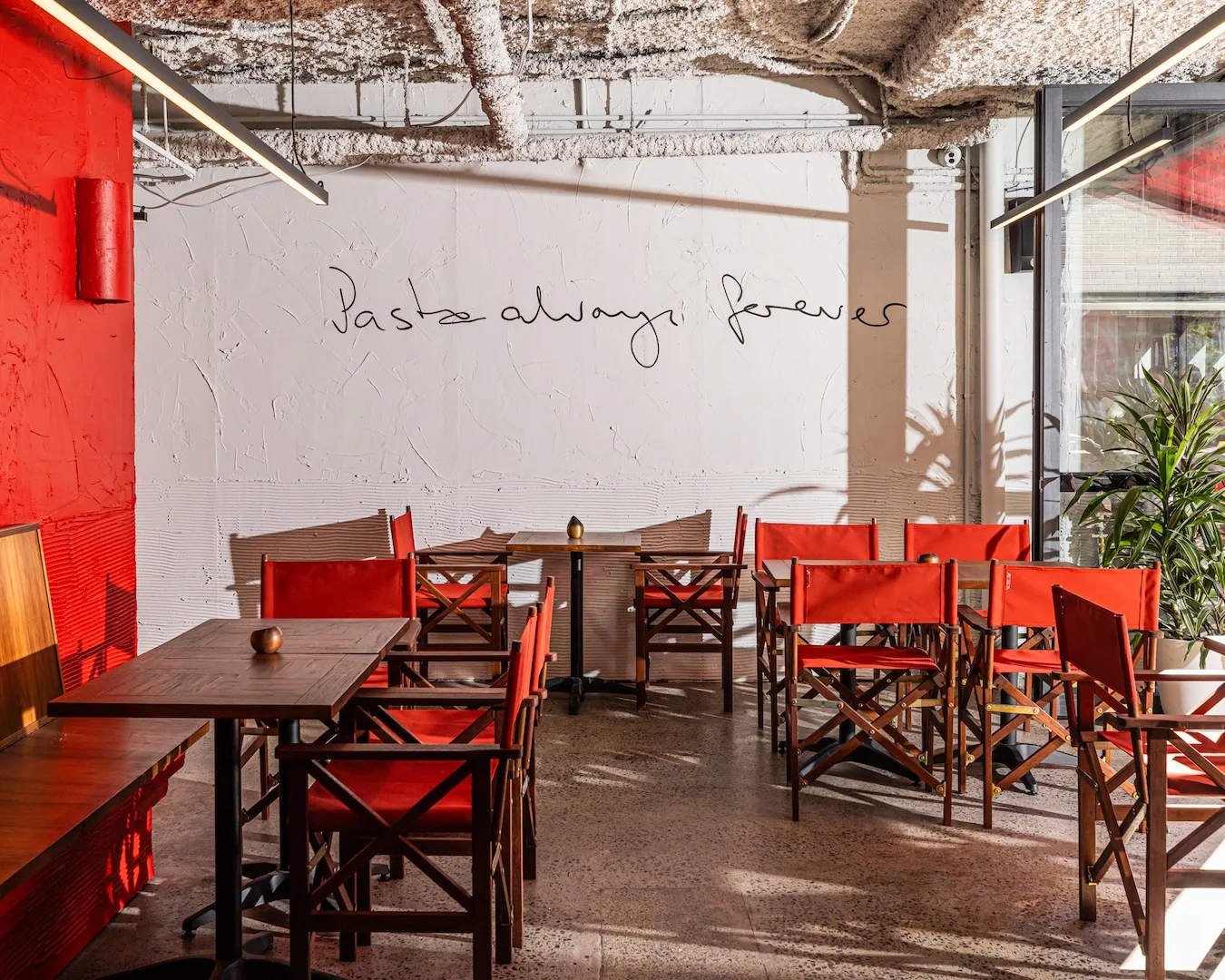 The dining room at new Sydney restaurant Pasta Shop, in Potts Point. A wall mural reads "Pasta always forever".