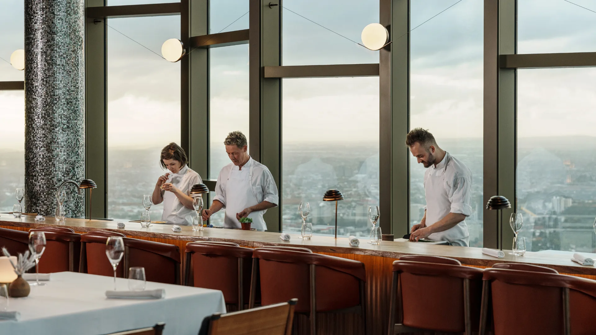 Chefs at work at Table Nineteen at Melbourne restaurant Atria, set against a backdrop of Melbourne views