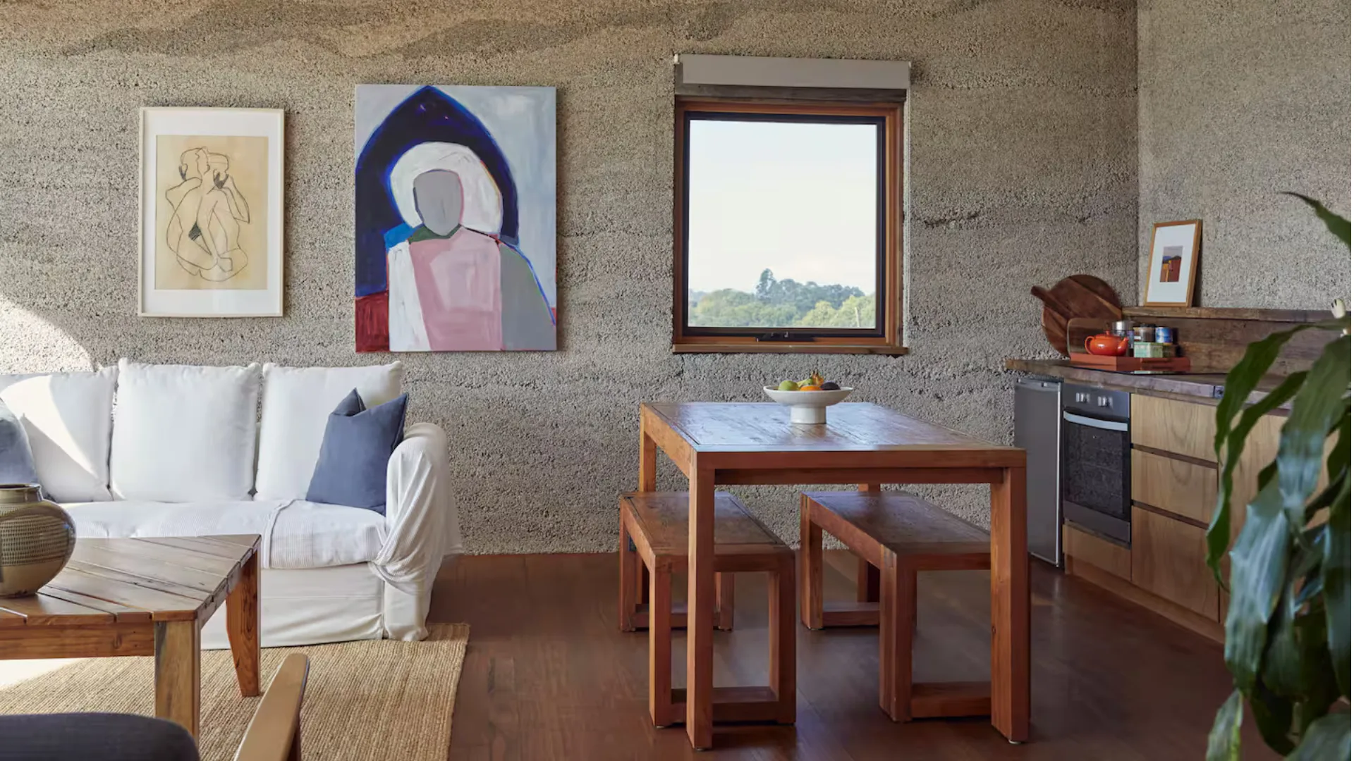 Skyview Hemp Villa, featuring a kitchen area with exposed lime rendered hempcrete wall, timber work surface, stainless sink & drainer, 4 ring halogen hob, oven, bar fridge & dishwasher. An Airbnb in Byron Bay