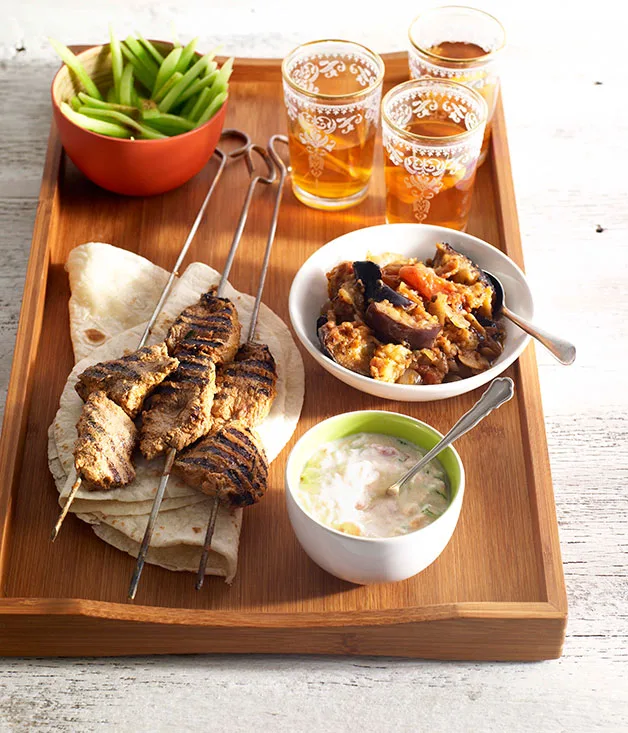 Lamb tikka kebabs with spiced eggplant, tomato raita and cucumber salad