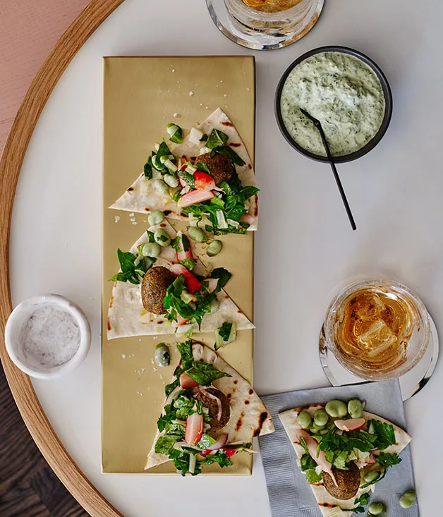 Pitas with broad bean felafels, green tahini sauce, pickled radish and herb salad