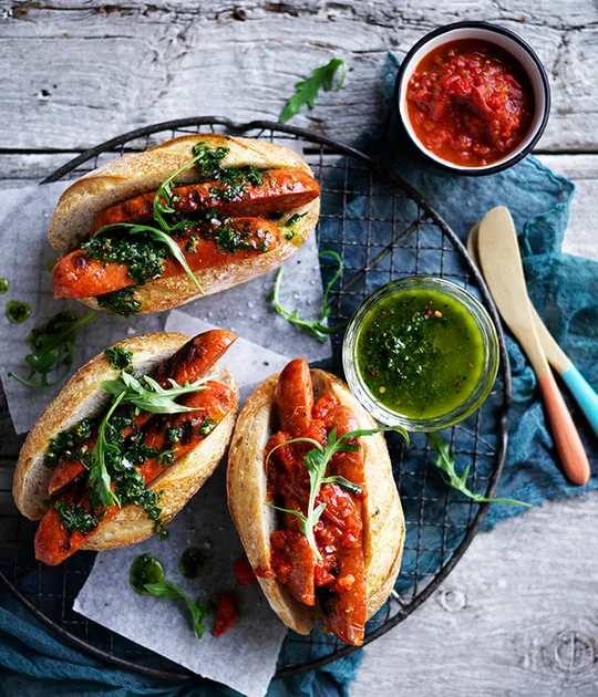 Chorizo hotdogs with chimichurri and smoky red relish recipe | Gourmet Traveller