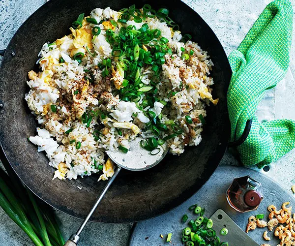 One pan Fried rice with crab, egg and cucumber in cast iron wok with wooden-handle serving spoon