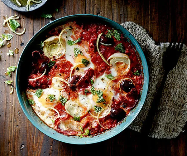 Baked eggs with artichoke, salami, tomato, olives and mint