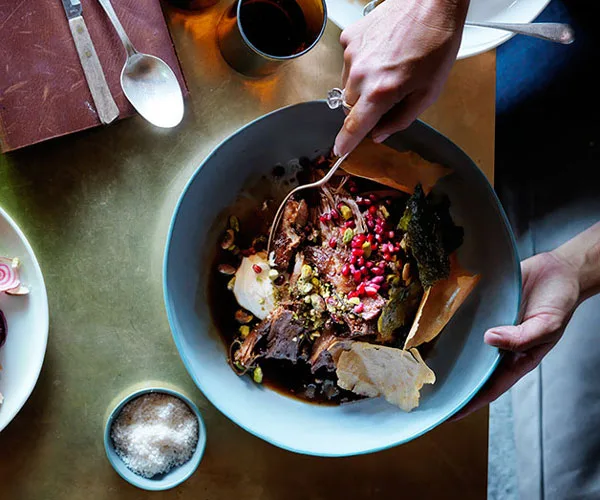 Slow-roasted lamb shoulder with pistachios, pomegranate and vine leaves