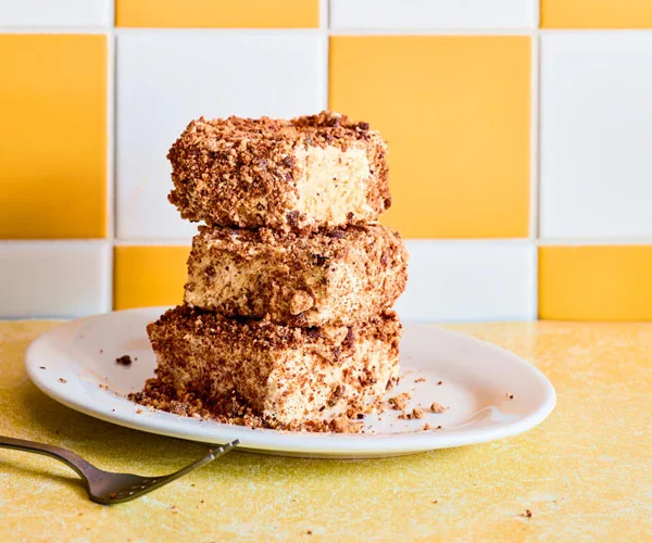 three cheesecake semifreddo squares stacked on top of eachother on white plate with yellow background