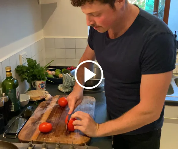 Toby Wilson chopping a tomato on a cutting board.