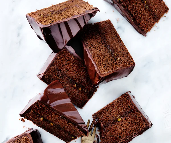 Triangular slices of iced chocolate cake on a marble off-white background.