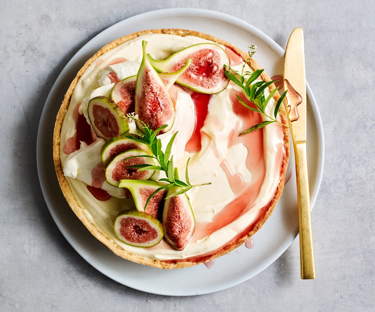 Over the top shot of a round tart topped withwhite chocolate and figs