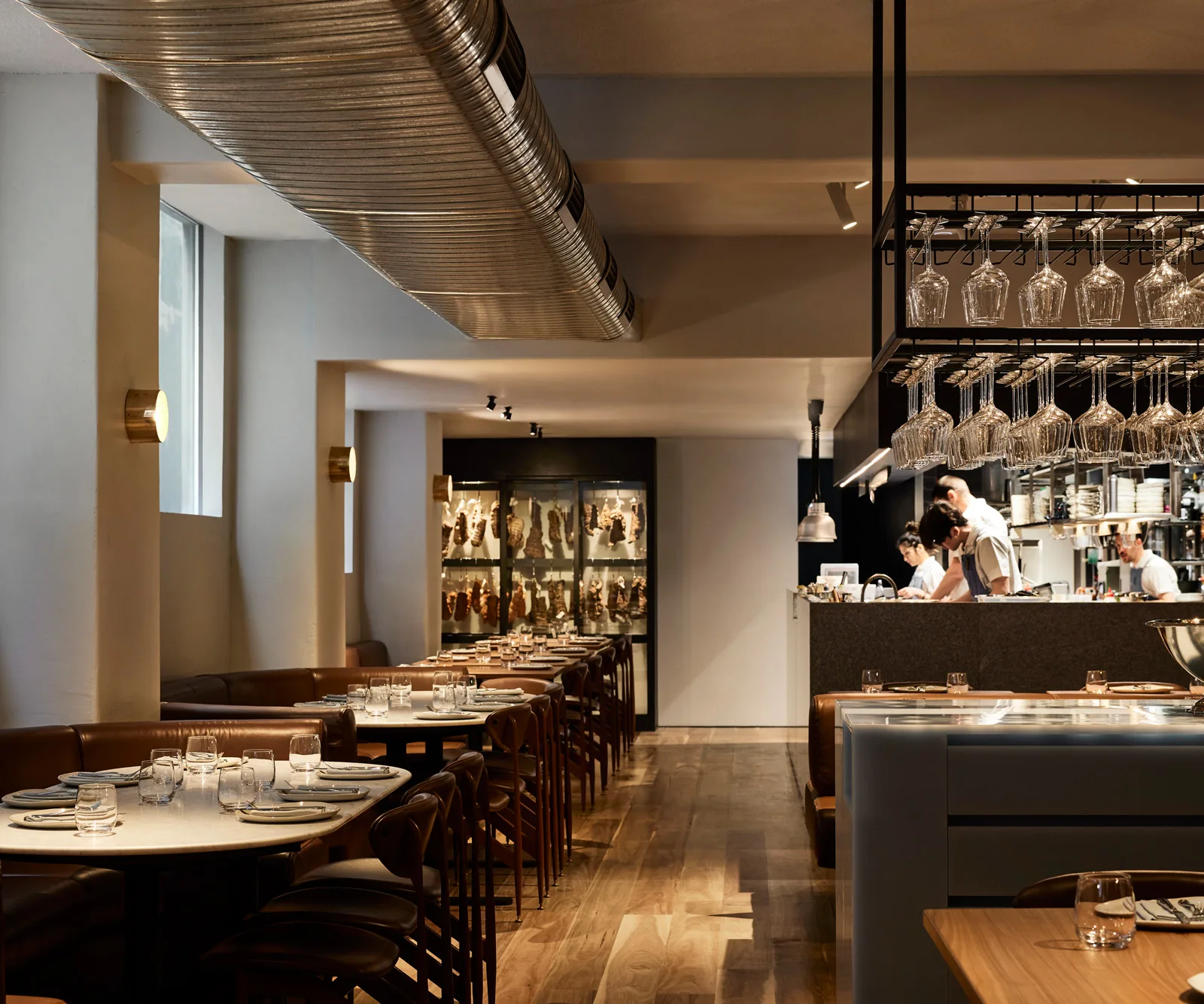 A landscape shot of the dining room, with booth seating to the left and a kitchen full of ched