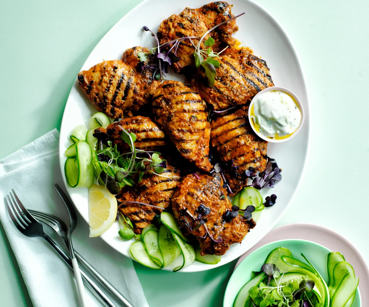 A plate of barbecued chicken thighs on a mint green background.