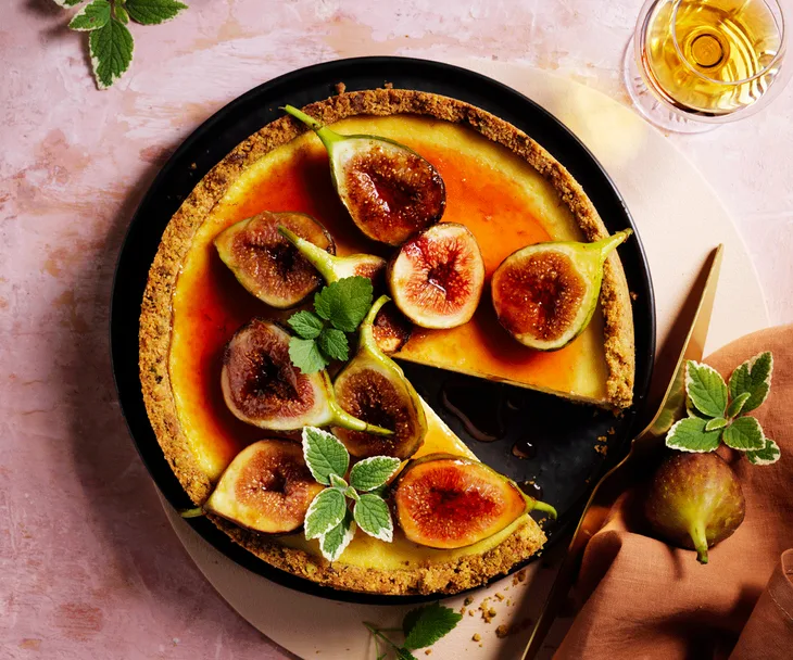 Cheesecake topped with halved figs and golden-orange syrup.