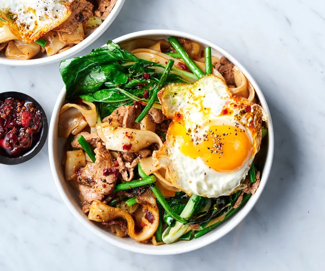 bowl of Cambodian noodle dish lort cha with Asian greens and fried egg