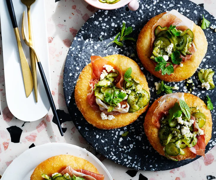 Bird's eye view of fried dough topped with ricotta, prosciutto and zucchini