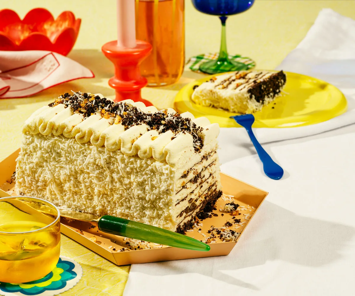 photo of colourful table setting with rectancgular ice-cream cake topped with chocolate crumb in the centre