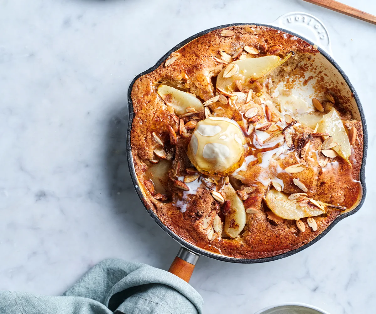 flat-lay photo of pear, Spiced pear, buttermilk and almond cake in a skillet