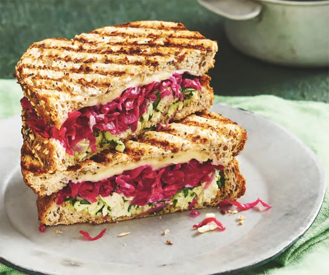 Grilled sandwich with red cabbage and greens on a plate.