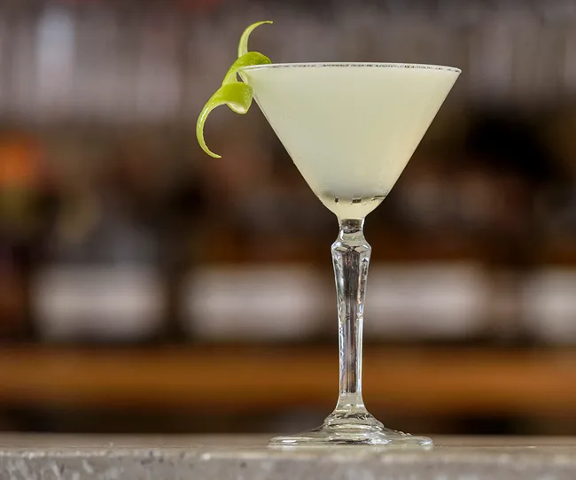 A classic daiquiri cocktail with a lime twist garnish, served in a martini glass.