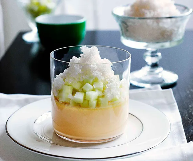 Chilled dessert in a glass with diced cucumber, ice granita, and creamy base on a white plate.
