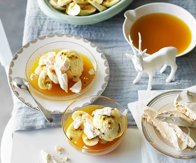 Plates of passionfruit ice cream with meringue on a table, next to a white decorative deer and sauce dish.