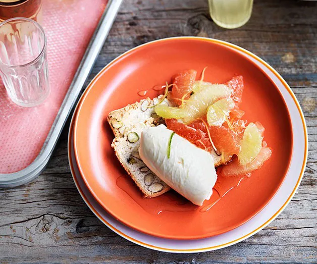 Orange plate with biscotti, sorbet, grapefruit slices, on rustic wooden table.