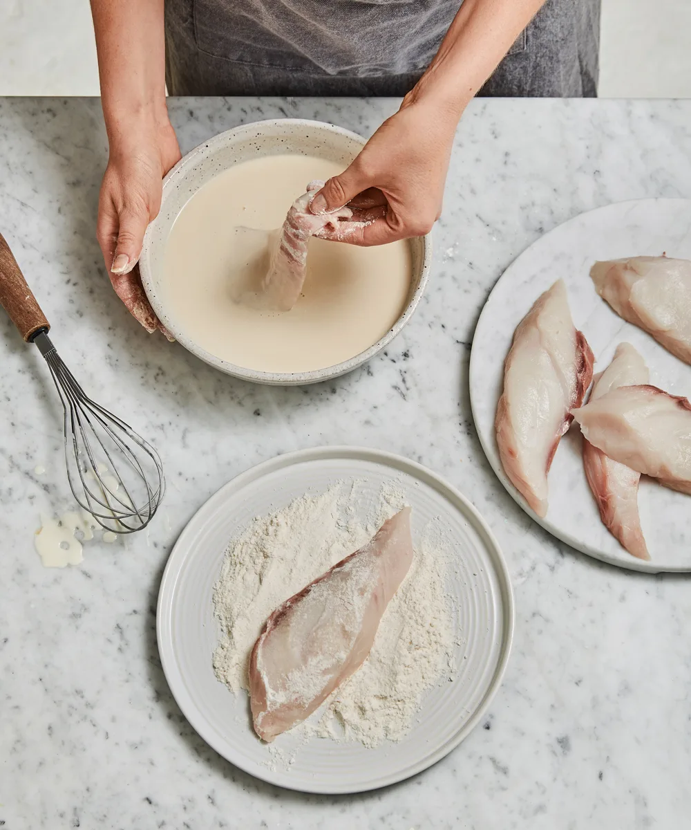 Dipping the fish into the batter to prepare for deep frying