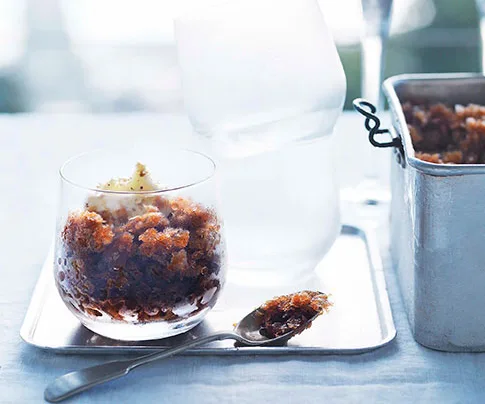 Glass of coffee granita with whipped cream on a tray, spoon beside, and a metal container of more granita.
