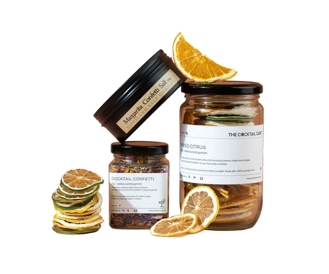 Jars of Margarita confetti salt, cocktail confetti, and mixed citrus slices, with dried orange slices on top.
