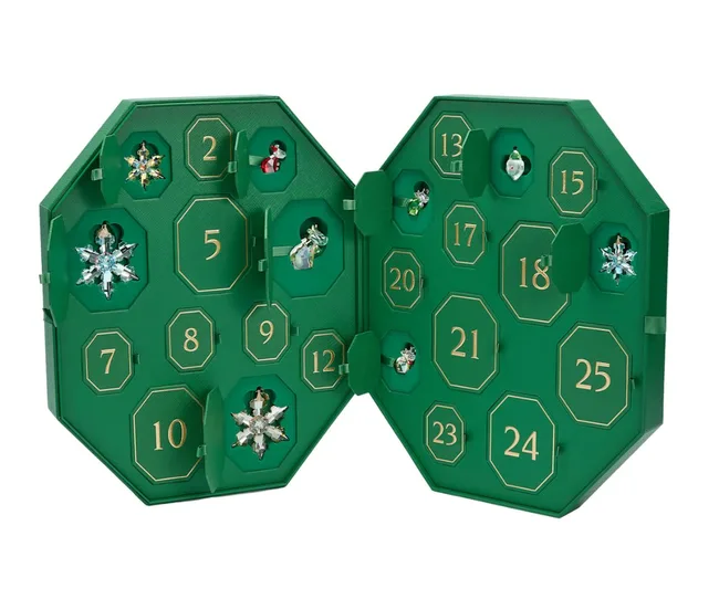 Green Advent calendar with numbered doors, opened to reveal various jewelry pieces including snowflakes and figurines.