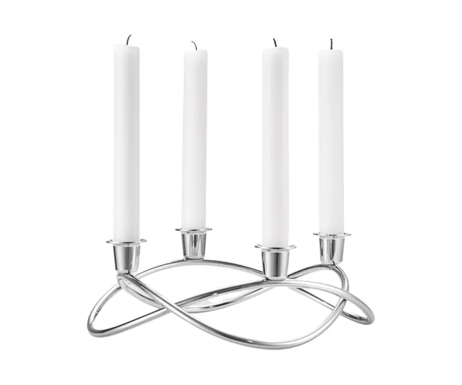 Silver candle holder with four white candles on a sleek, intertwined metal design against a white background.