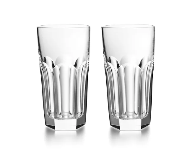 Two clear, faceted crystal highball glasses against a white background.