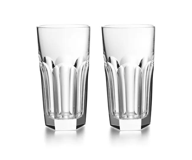 Two clear, faceted crystal highball glasses against a white background.