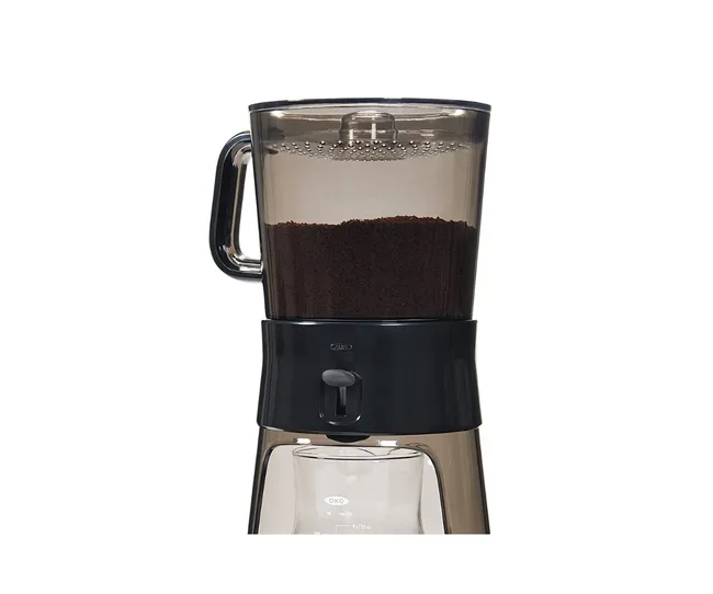 OXO coffee maker with grounds in the brewing compartment and a carafe below.