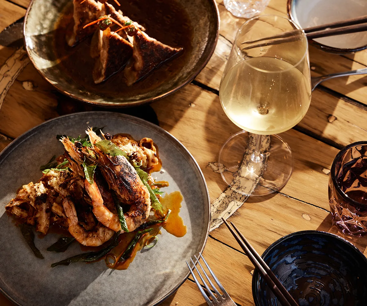 The Little Rickshaw in Aldinga, Adelaide SA. Photo of a plate of prawns with chilli, and a plate of potsticker dumplings served with a glass of white wine