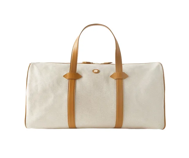 Cream canvas duffel bag with brown leather handles and accents.