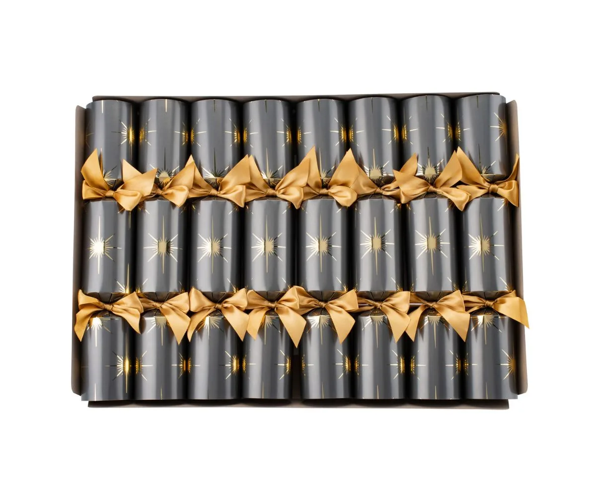 Box of Christmas crackers in dark paper with gold star and ribbon decoration, arranged neatly in rows.
