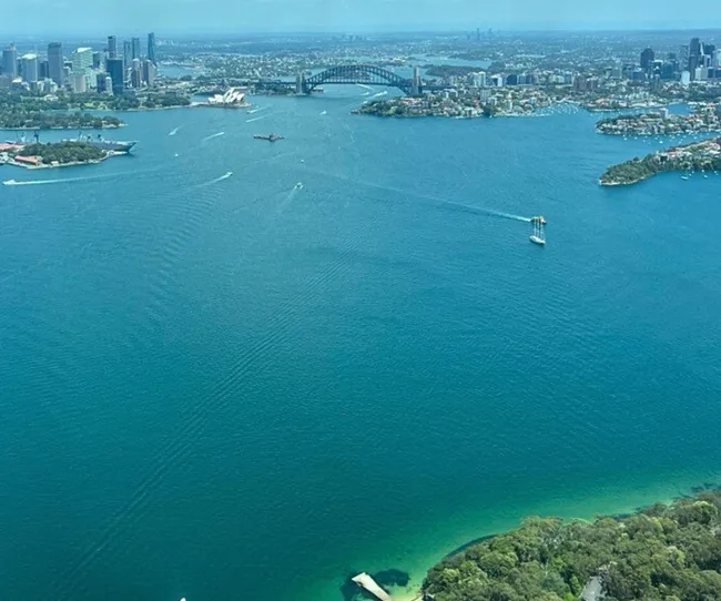 Aerial view of Sydney Harbour with the Opera House and Harbour Bridge in the background on a clear day.