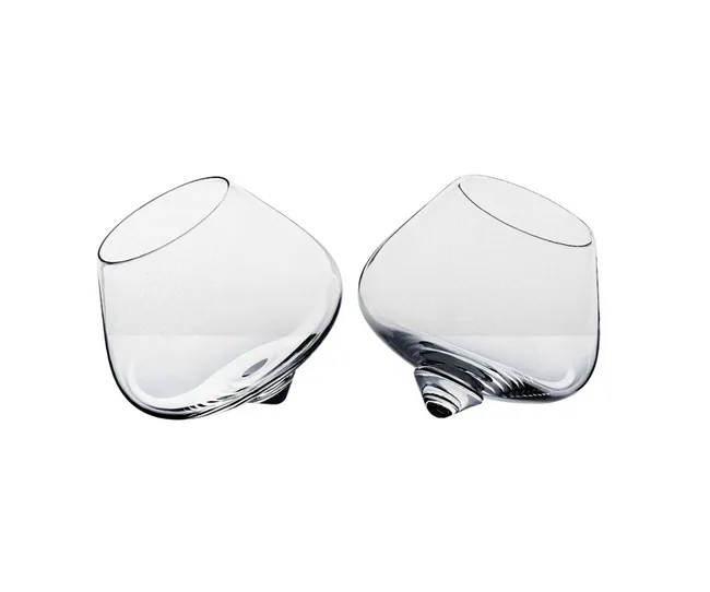 Two tilted, clear, round-bottomed whiskey glasses with a modern design.