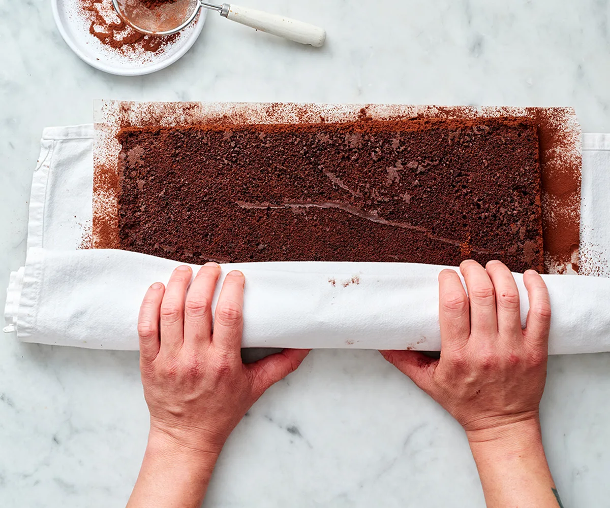 the sponge for a yule log being rolled in a tea towel to cool