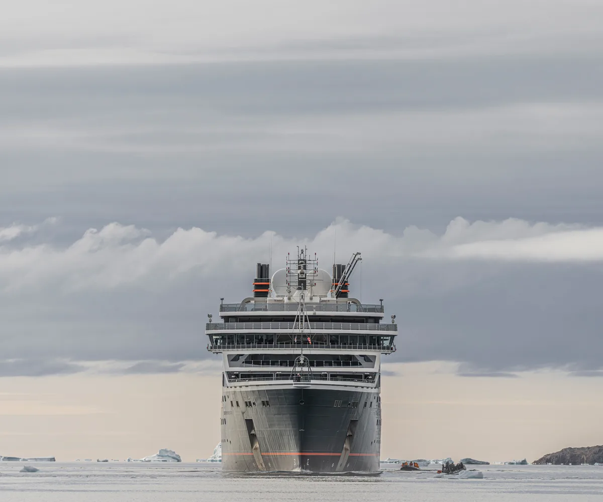 Front on view of the Seabourn Venture cruise, plunging through icy water