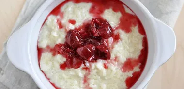 Creamy coconut rice pudding with poached strawberries and red grapes