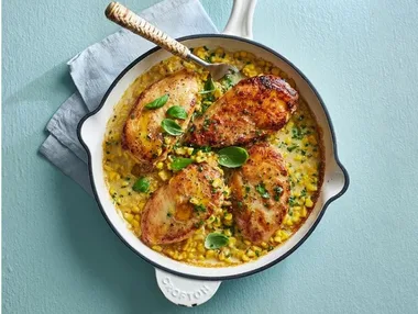 skillet with chicken fillets and corn in creamy sauce