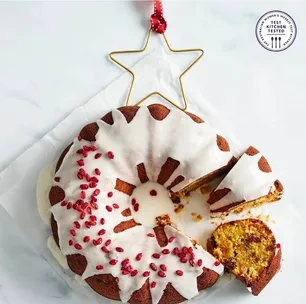 circular cake with white icing and topped with a wire chrstmas star, decorated with dried berries