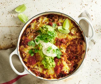 burrito bake with cheese and spring onion topping in a white dish