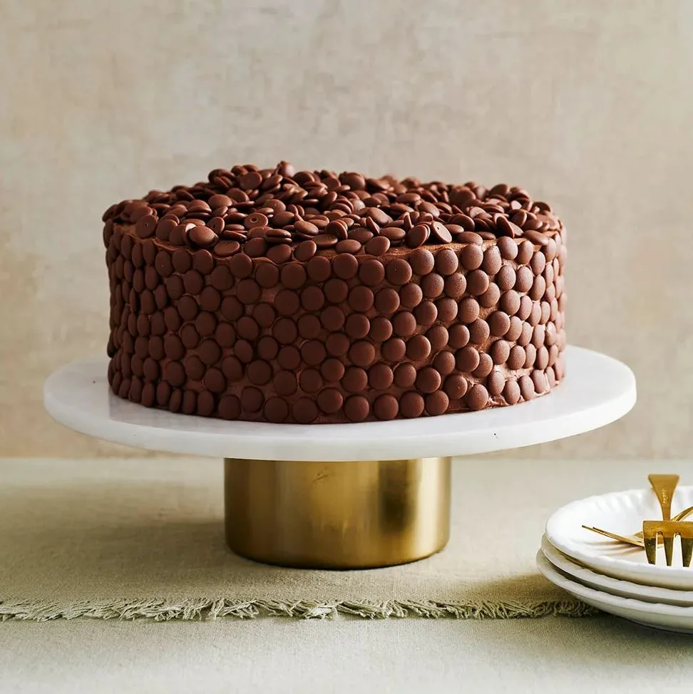 chocolate cake decorated with chocolate drops on marble cake tray