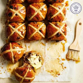 fresh hot cross buns, one cut in half and buttered